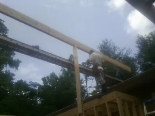 Carpenter setting a ridge beam over a new addition frame — Ice Dam Removal by Roofing Brothers in East China