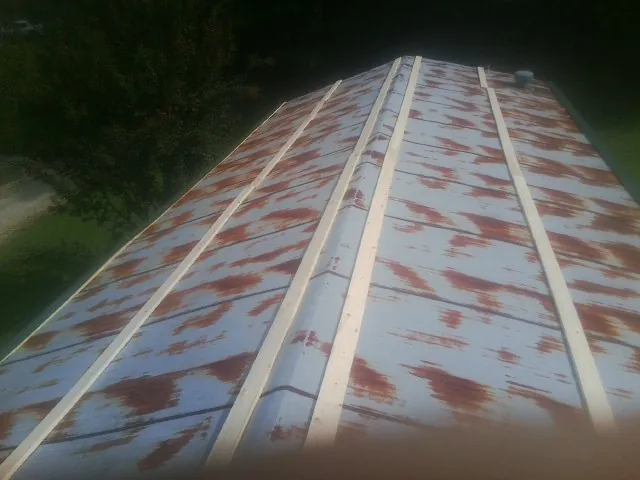 Rusted metal roof panels with new wood purlins before replacement — Storm Damage Roof Repair in East China by Roofing Brothers