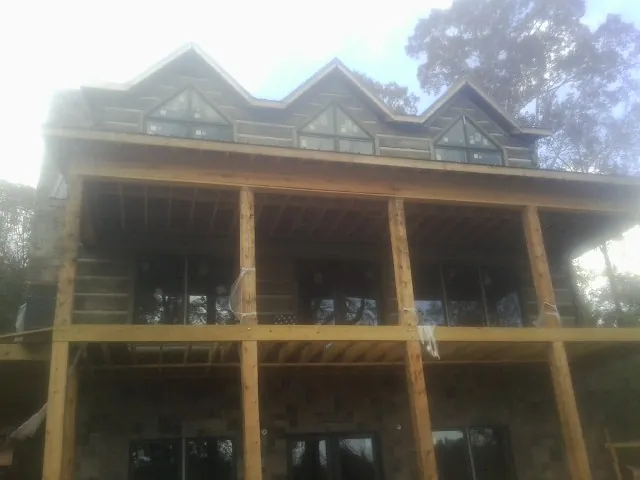 Dormers and porch framing on a large log home under construction — Roof Coating work by our crew in East China