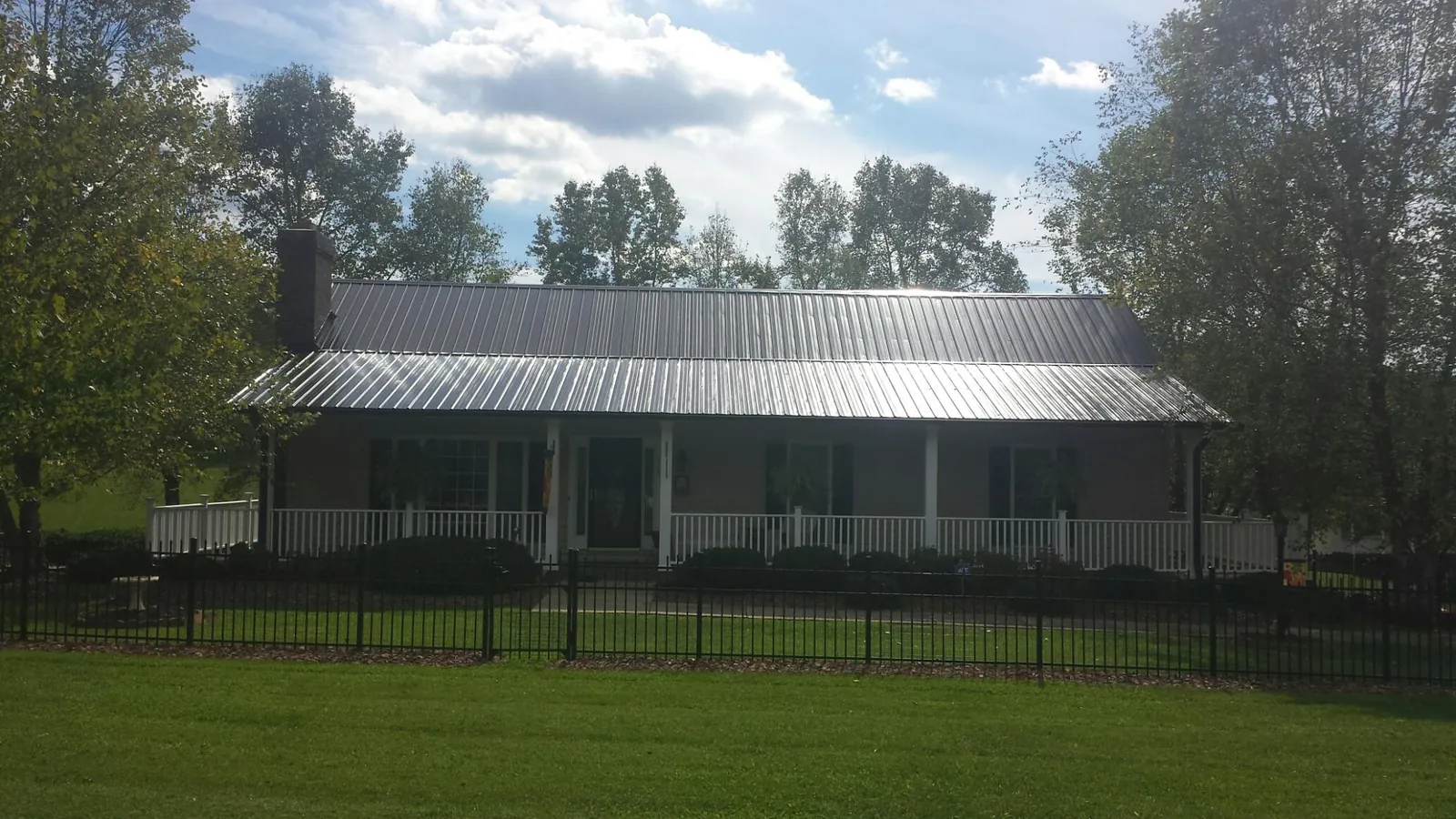 Gray metal roof on a brick ranch with a full width front porch — Gutter Guard Installation work by our crew in East China