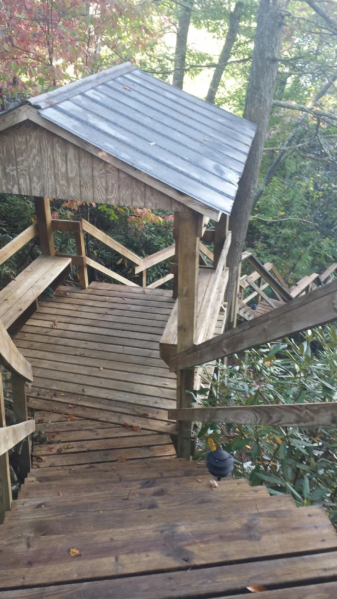 Metal roofed shelter over wooden steps on a wooded walkway — Skylight Repair & Installation work by our crew in East China