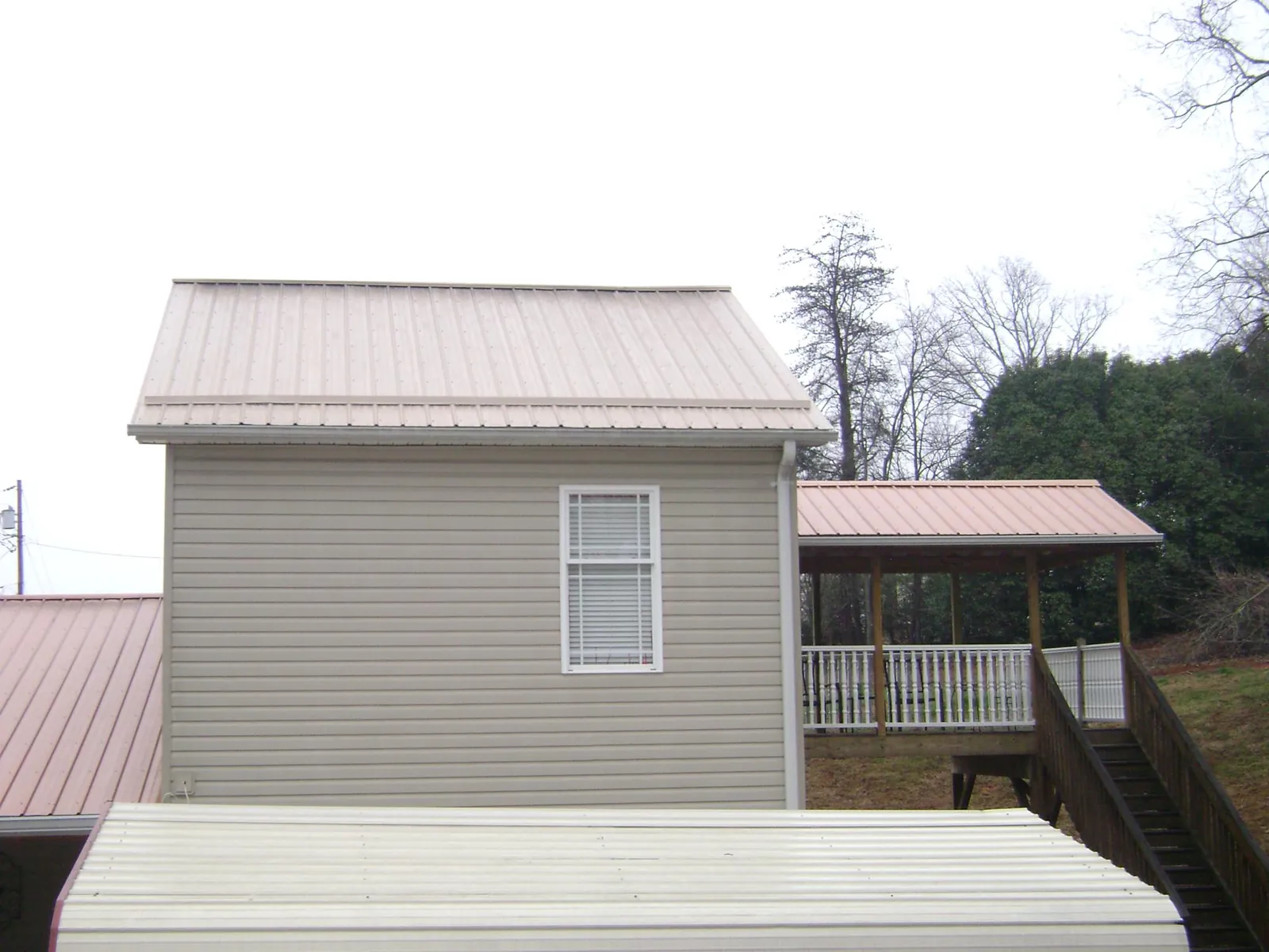 Tan metal roofs on a two story addition and attached porch, from a Roof Replacement job in East China