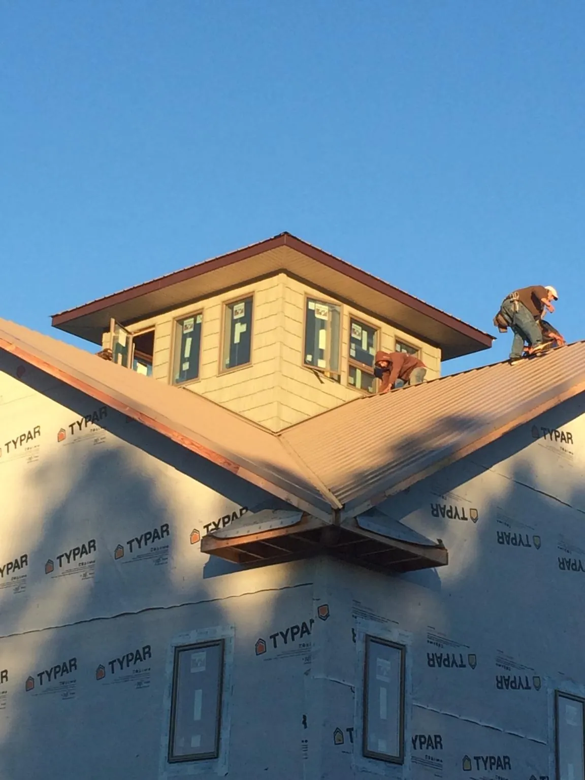 Roofers working around a rooftop cupola on a new metal roof at sunset — Roof Waterproofing in East China by Roofing Brothers